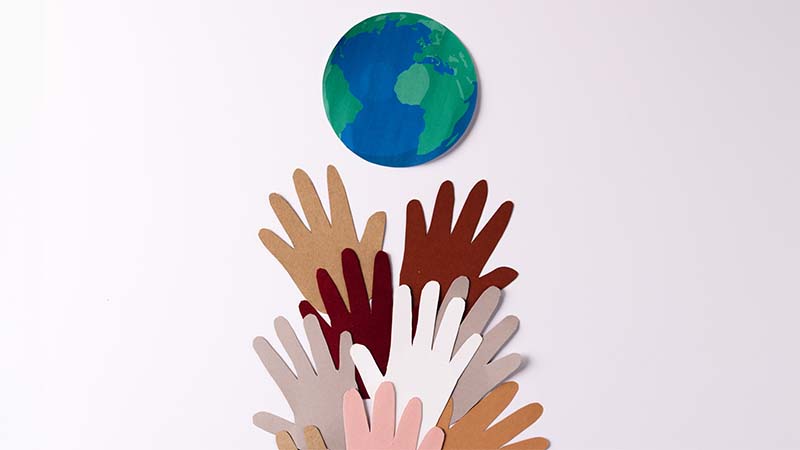 Paper Cut Out Of Multi Coloured Hands With Globe